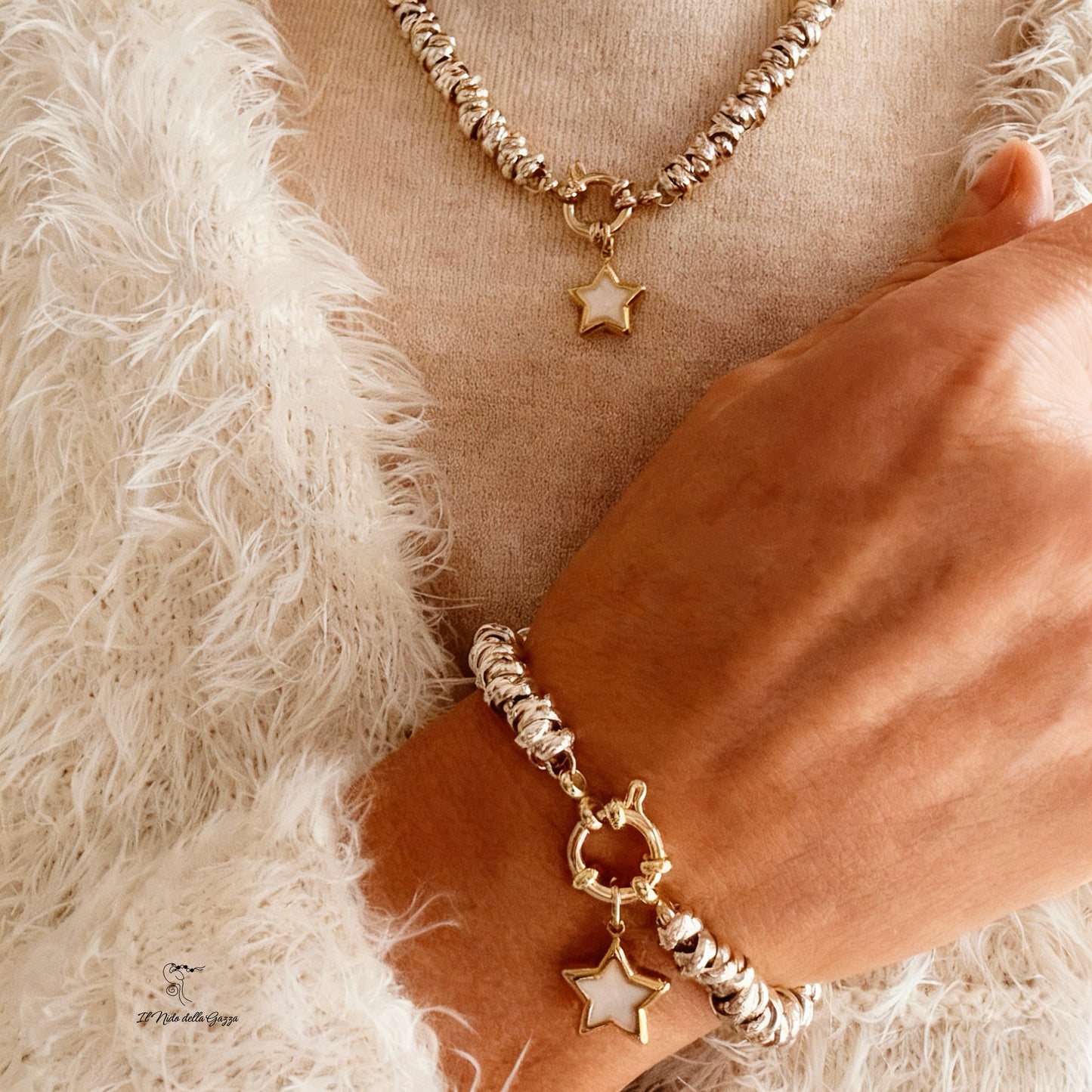 Set collana e bracciale dorati indossati, con ciondolo a stella madreperlata.