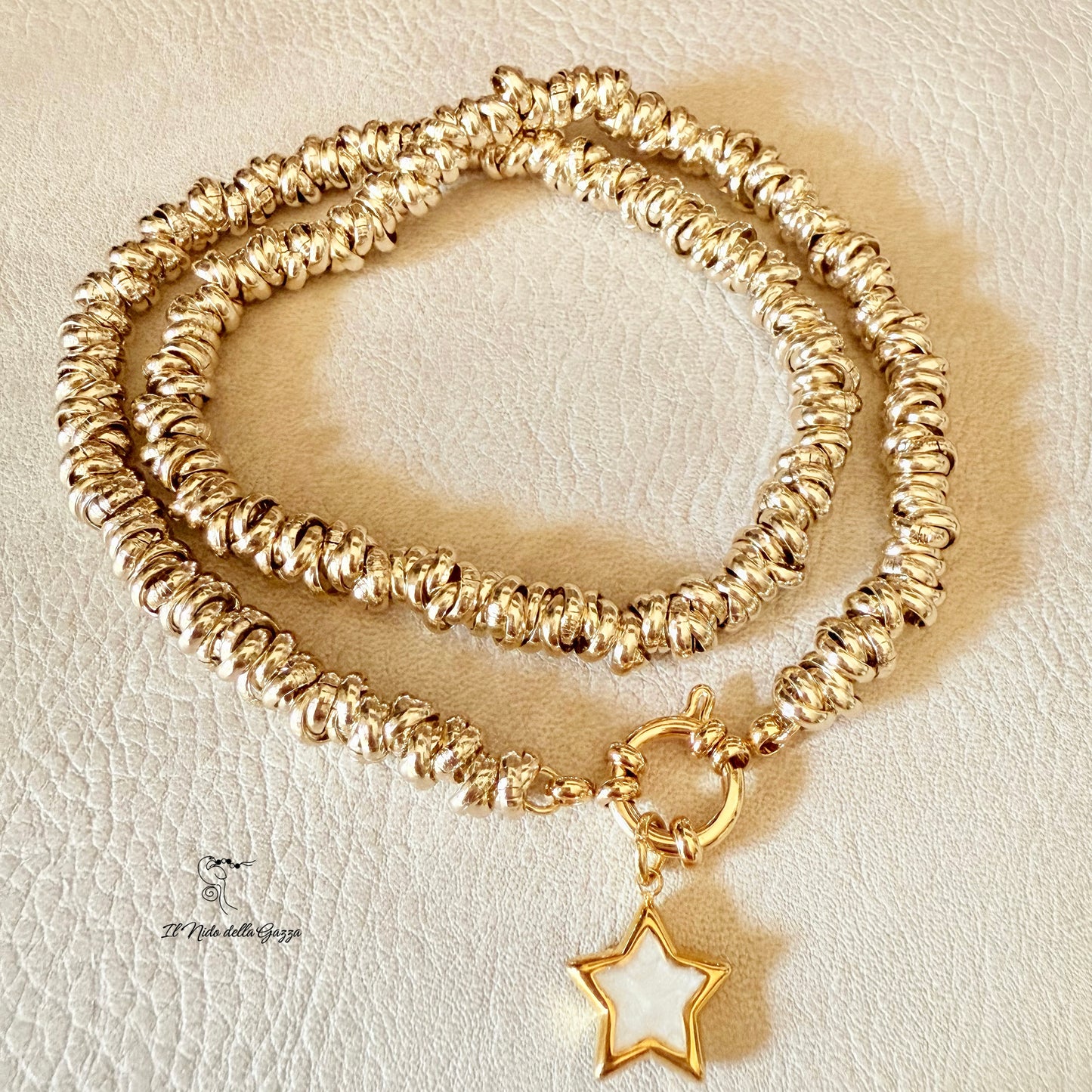 	Collana dorata con ciondolo a stella in madreperla su sfondo chiaro.