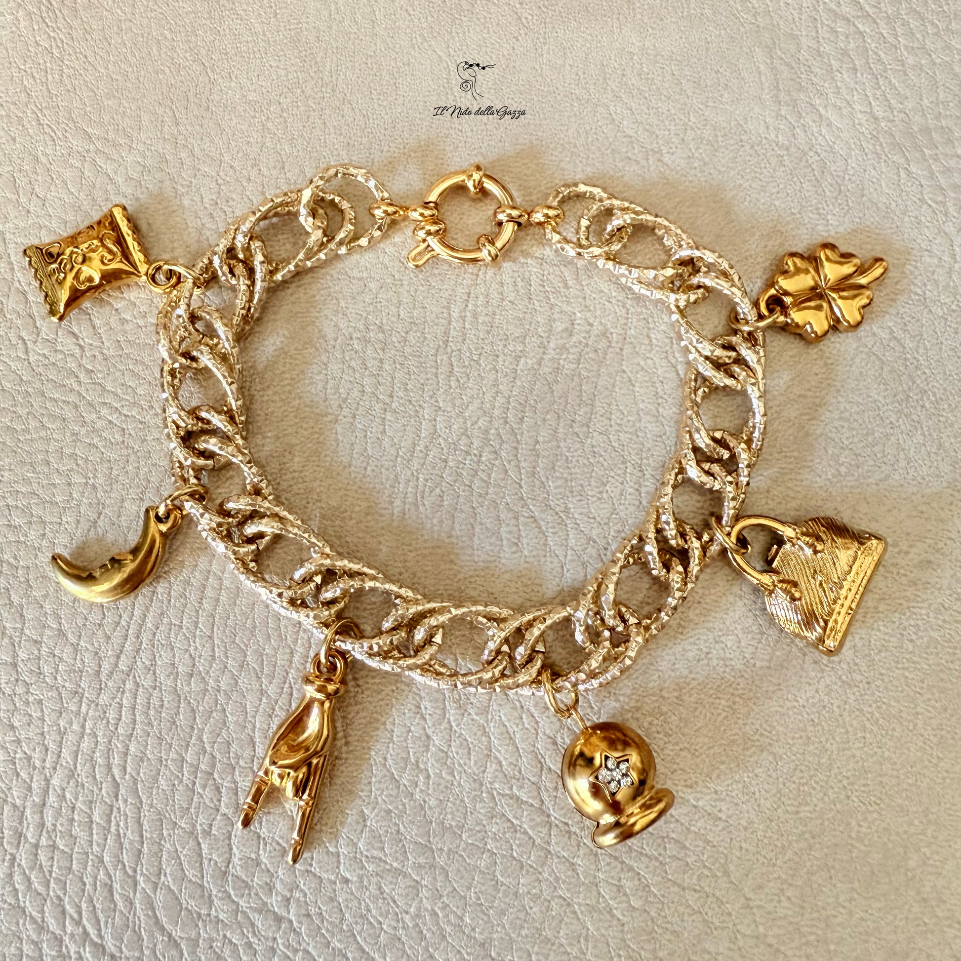 Bracciale dorato con charm portafortuna su sfondo chiaro 