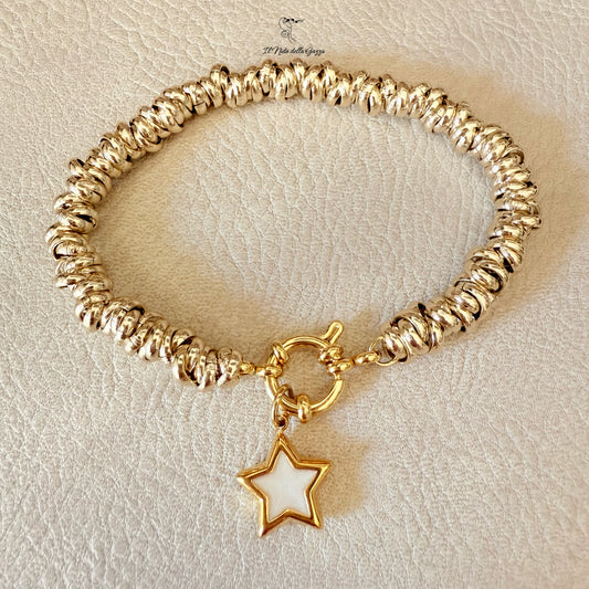 Bracciale dorato con stella in madreperla su sfondo panna 
